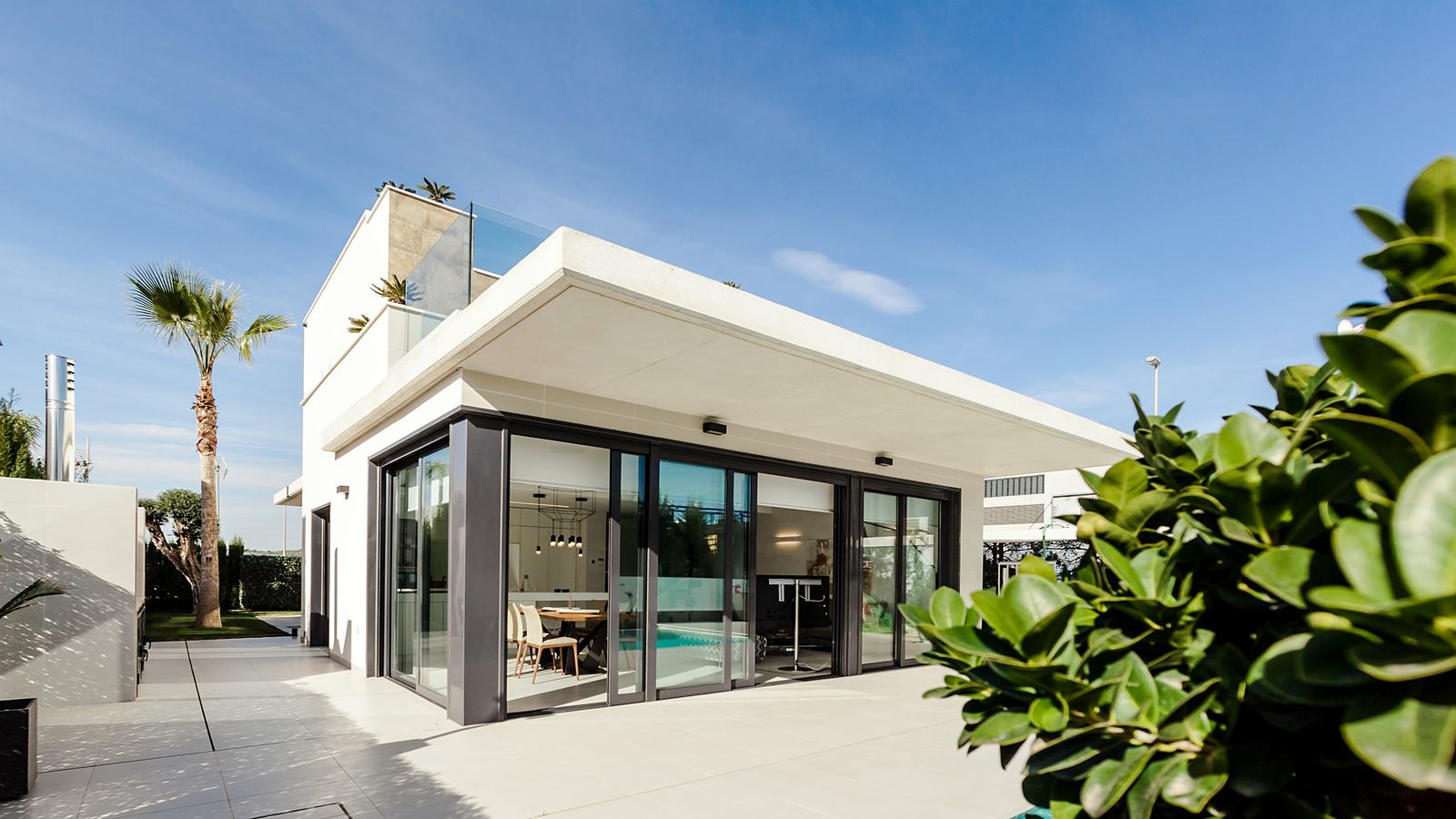 Modern white home with floor-to-ceiling glass doors and a landscaped garden